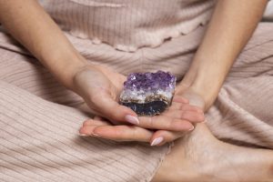 hands holding purple crystal